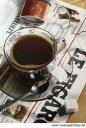 прозрачная чашка с кофе на газете